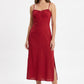 A woman modeling a red midi-length spaghetti-strap dress with a gathered sweetheart neckline and side slits, paired with beige pointed-toe heels, against a plain white studio background.
