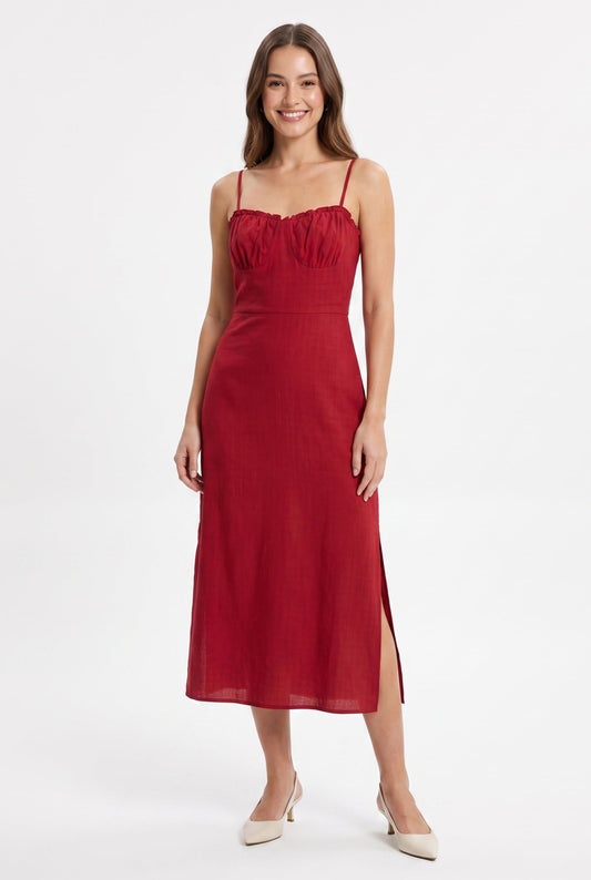 A woman modeling a red midi-length spaghetti-strap dress with a gathered sweetheart neckline and side slits, paired with beige pointed-toe heels, against a plain white studio background.